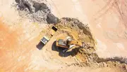 Aerial view of excavator loading a dump truck at an open mining site, representing heavy-duty machinery applications requiring effective oil filtration for reliable operation.