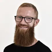 Employee portrait of a production coordinator wearing glasses in a workplace setting.