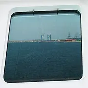 Marine window with integrated washing nozzles mounted in the frame for external glass cleaning.