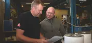Two employees reviewing documents together in a foundry production environment at C.C.JENSEN Casting.