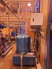 Industrial oil filtration system installed in a mining plant lubrication room with pipes and tanks.