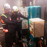 Two technicians in protective gear servicing an industrial oil filtration system on site.