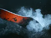 Heated metal component being quenched in oil during an industrial heat-treatment process.