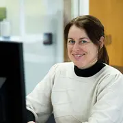 Employee portrait of a sales support team member smiling in an office environment.