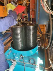 Technician servicing stacked depth filter inserts in an offline oil filtration unit for a ball mill lubrication system.