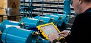 Technician inspecting CJC oil filtration units in a workshop, using a tablet to review system data and service information.