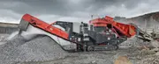 Mobile secondary cone crusher processing rock in a mining quarry.