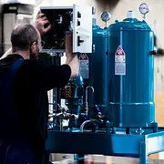 Technician working on a C.C.JENSEN filtration unit, representing efficient oil filtration and sustainable operation.